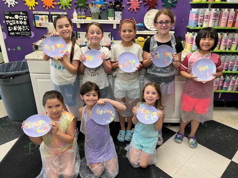 Children proudly displaying their painted plates.