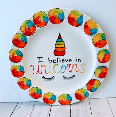 A plate with the words " i believe in unicorns ".
