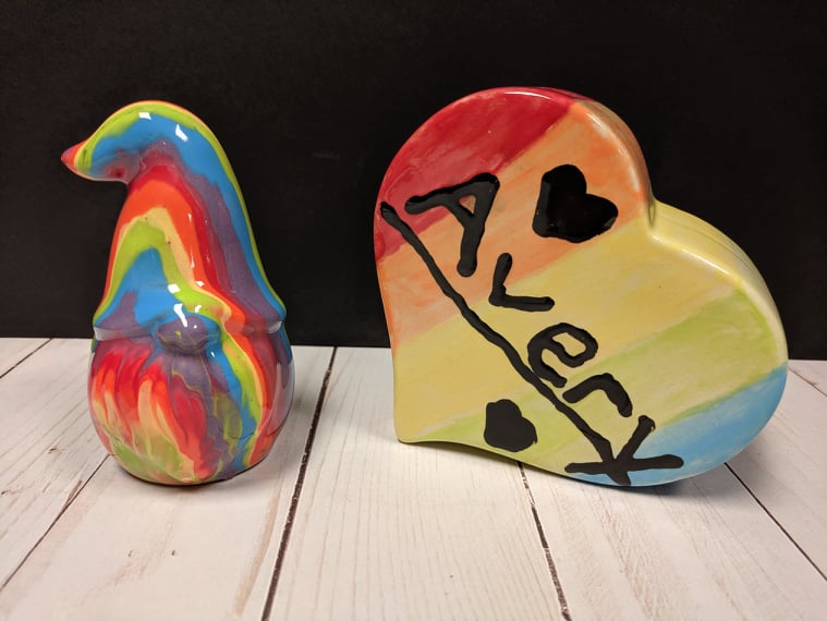 A colorful ceramic dwarf figurine placed beside a ceramic heart figurine