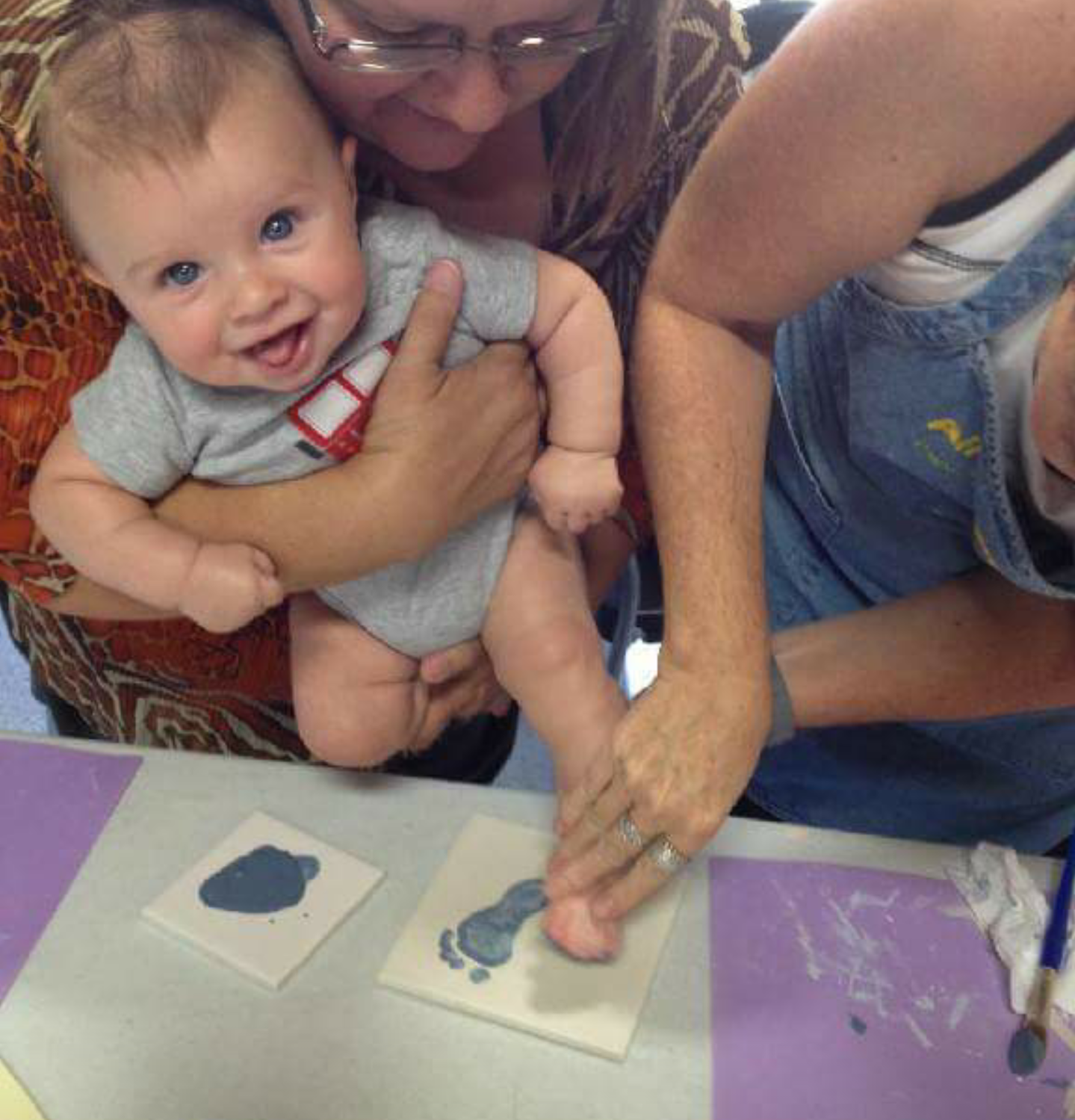 A woman holding a baby while they paint.