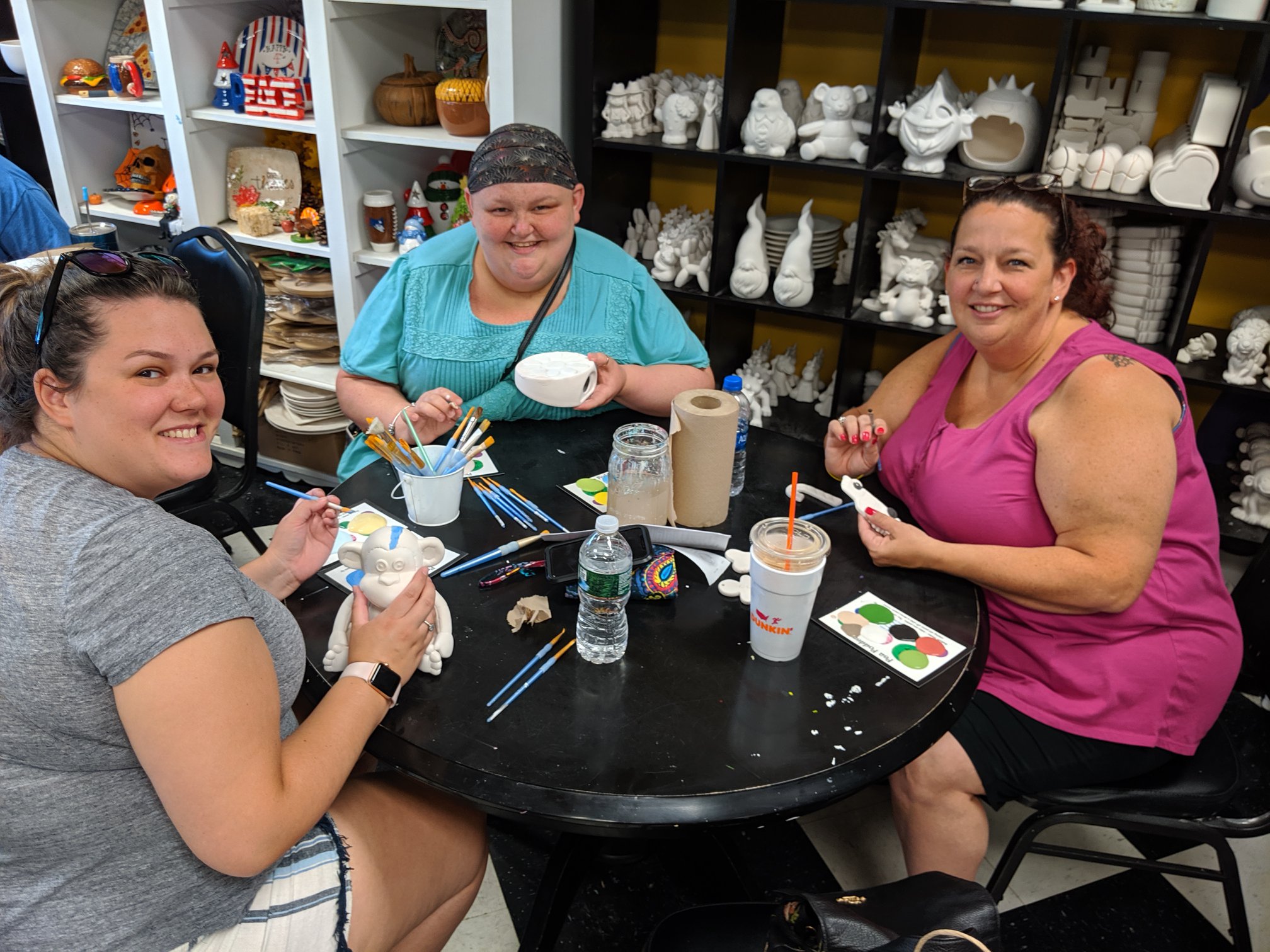 Three people sitting and doing ceramic painting activities