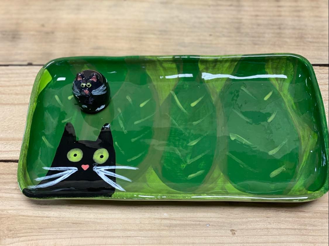 A green tray with a black cat on it