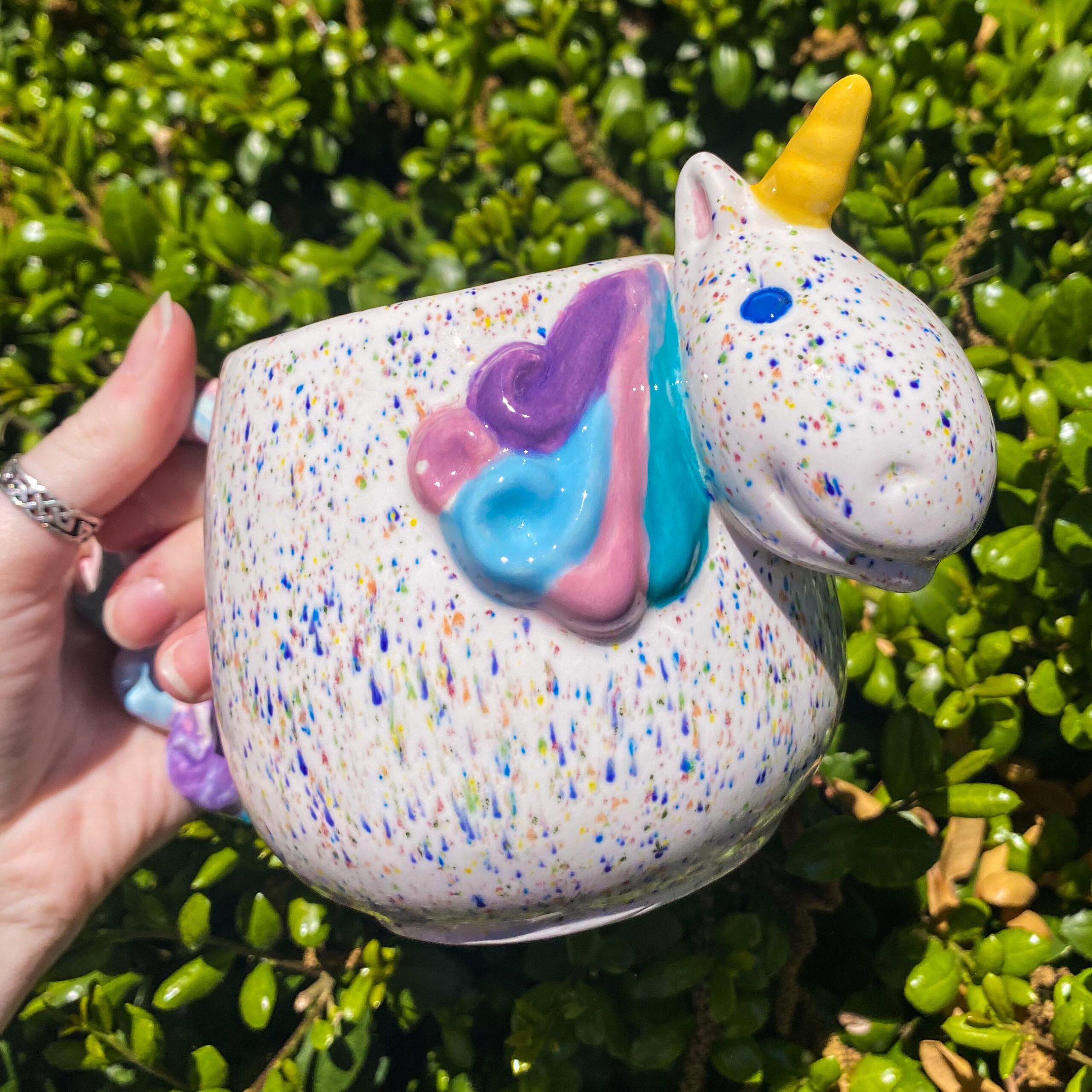 A person holding a unicorn shaped container in their hand.