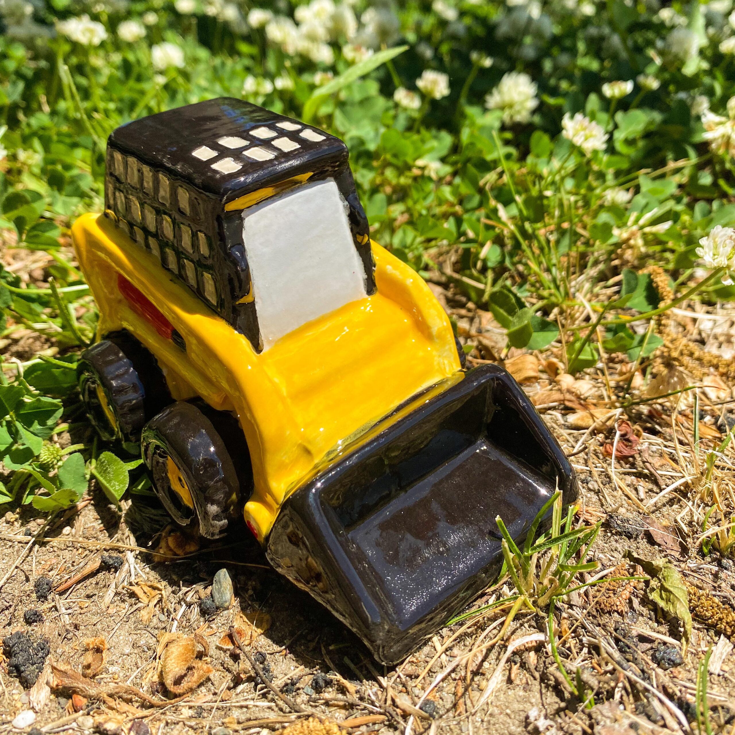 A toy tractor is sitting in the grass.