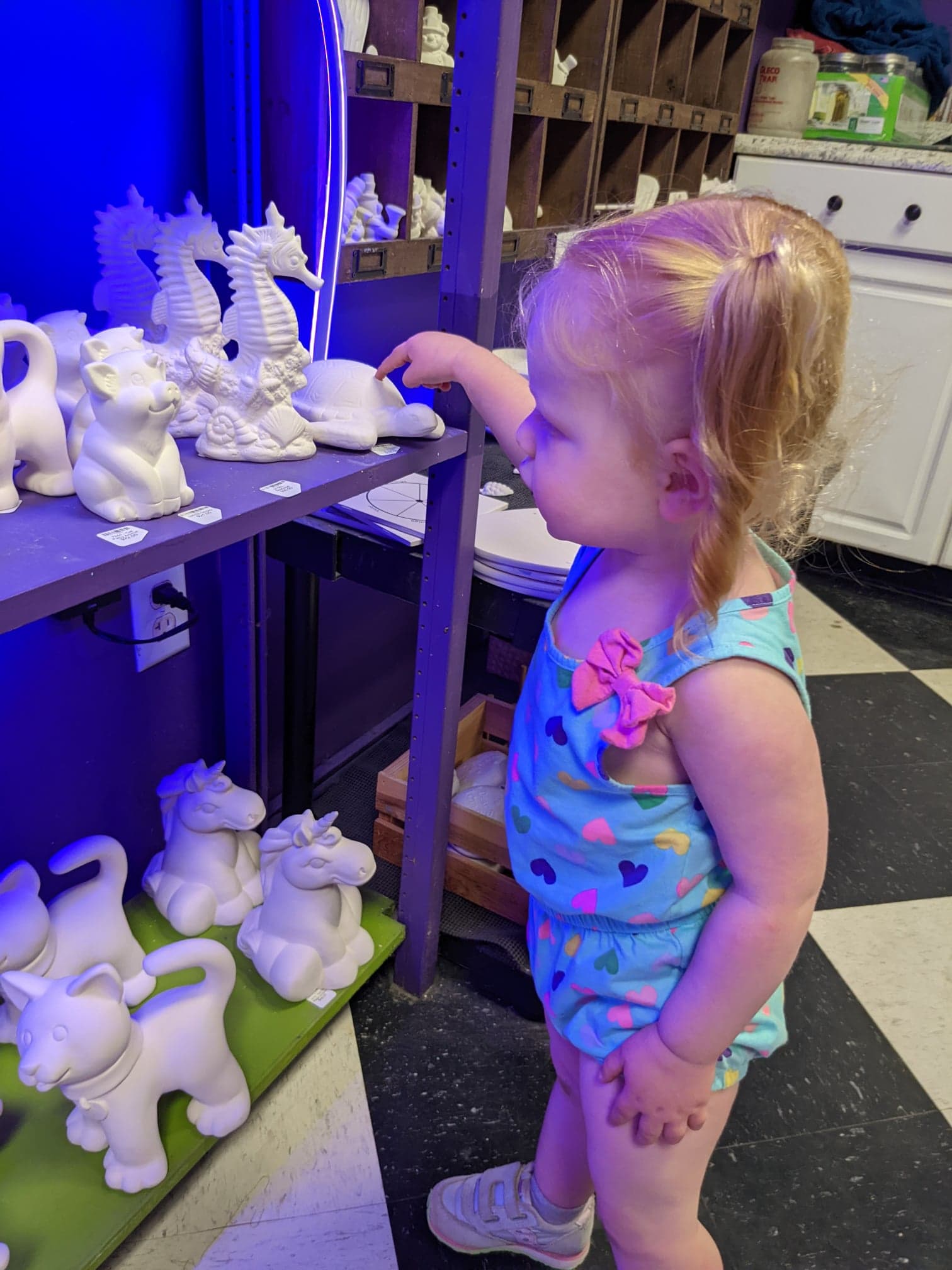 A little girl looking at some white ceramic figurines.