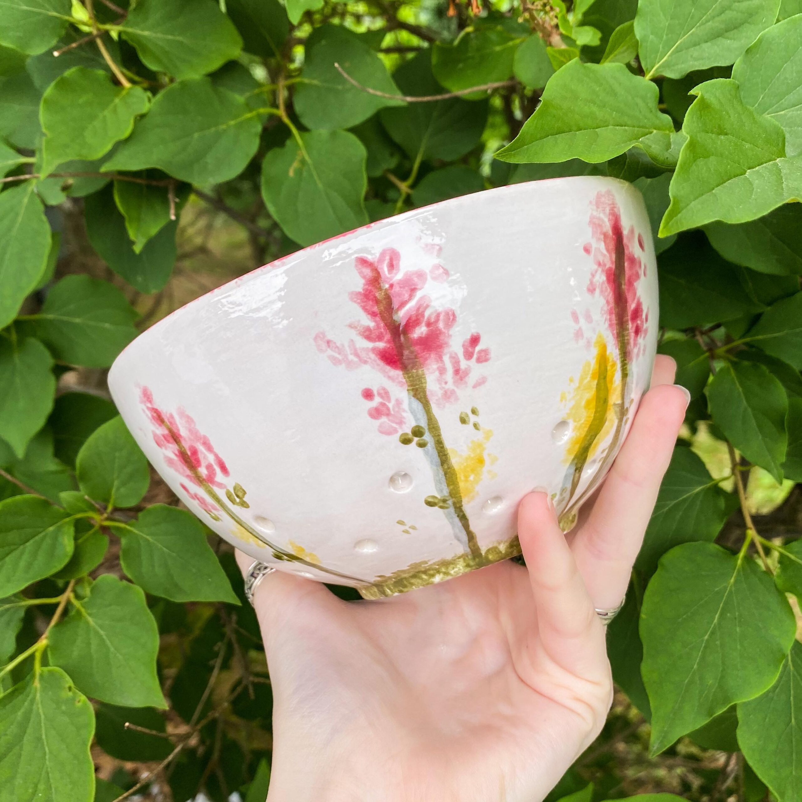 A hand holding a bowl with flowers on it.