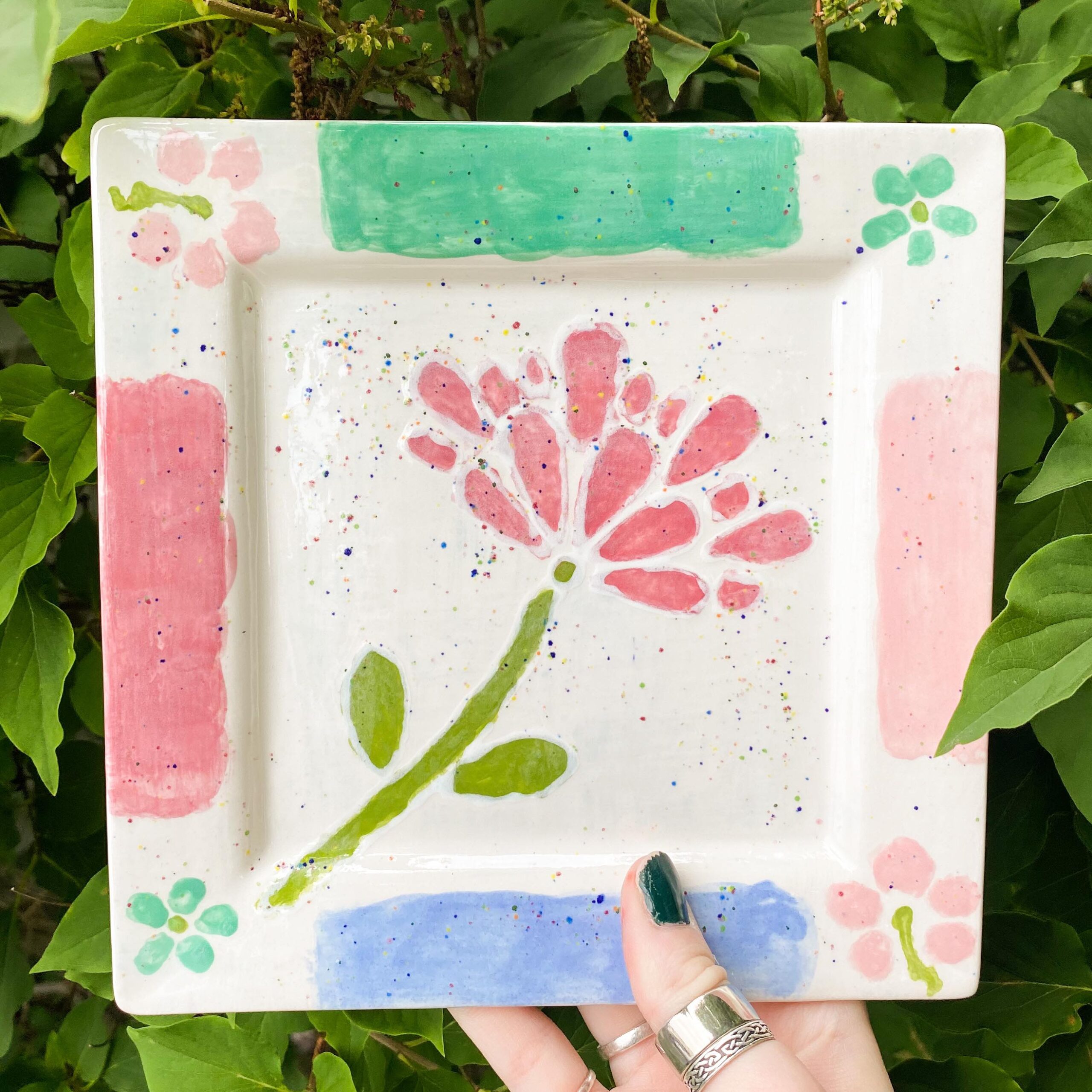 A hand holding up a plate with flowers on it.