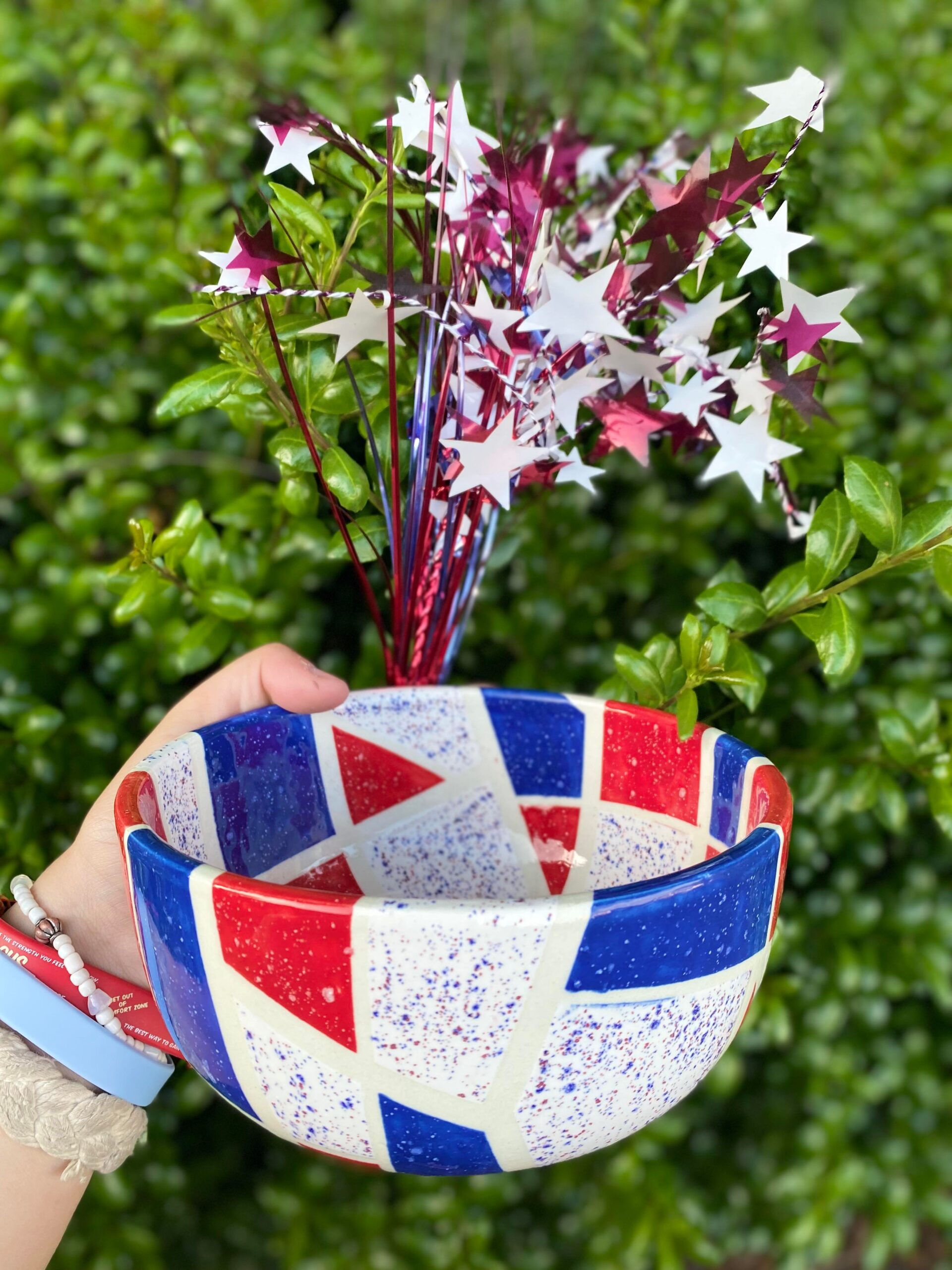 A person holding a bowl with red, white and blue designs on it.