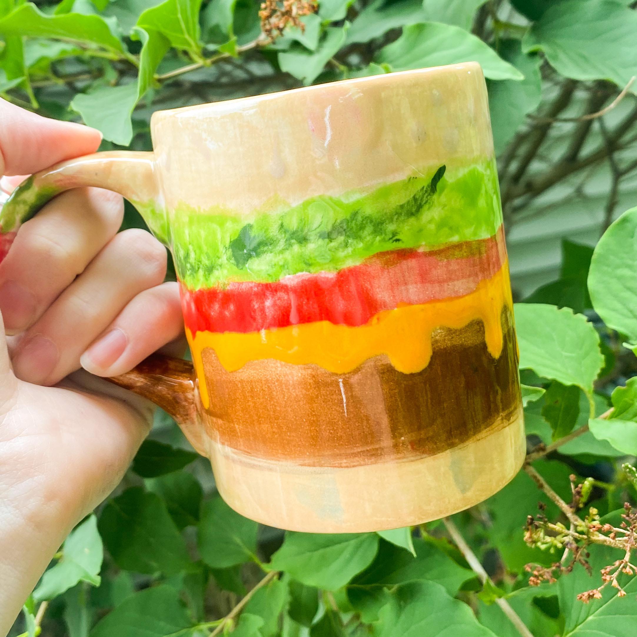 A person holding a cup with a hamburger on it.
