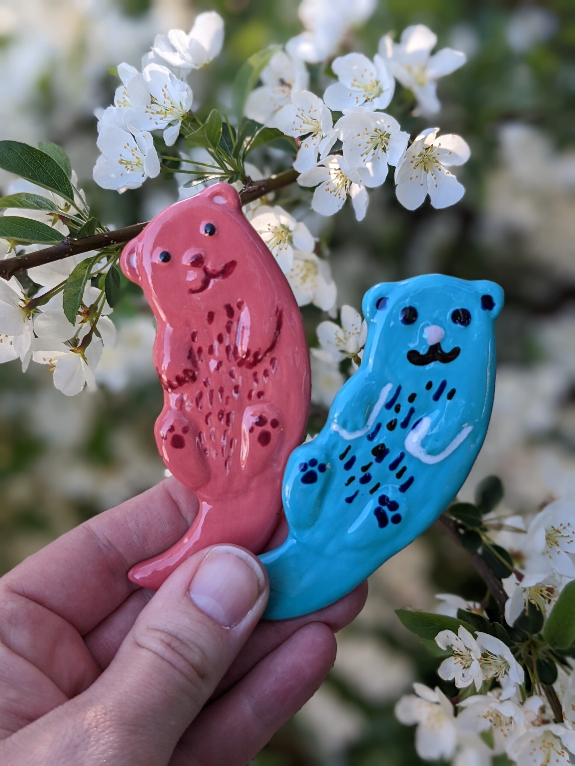 A hand holding two cookies shaped like animals.
