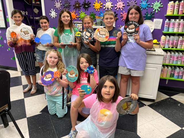 A group of children holding up paper plates.