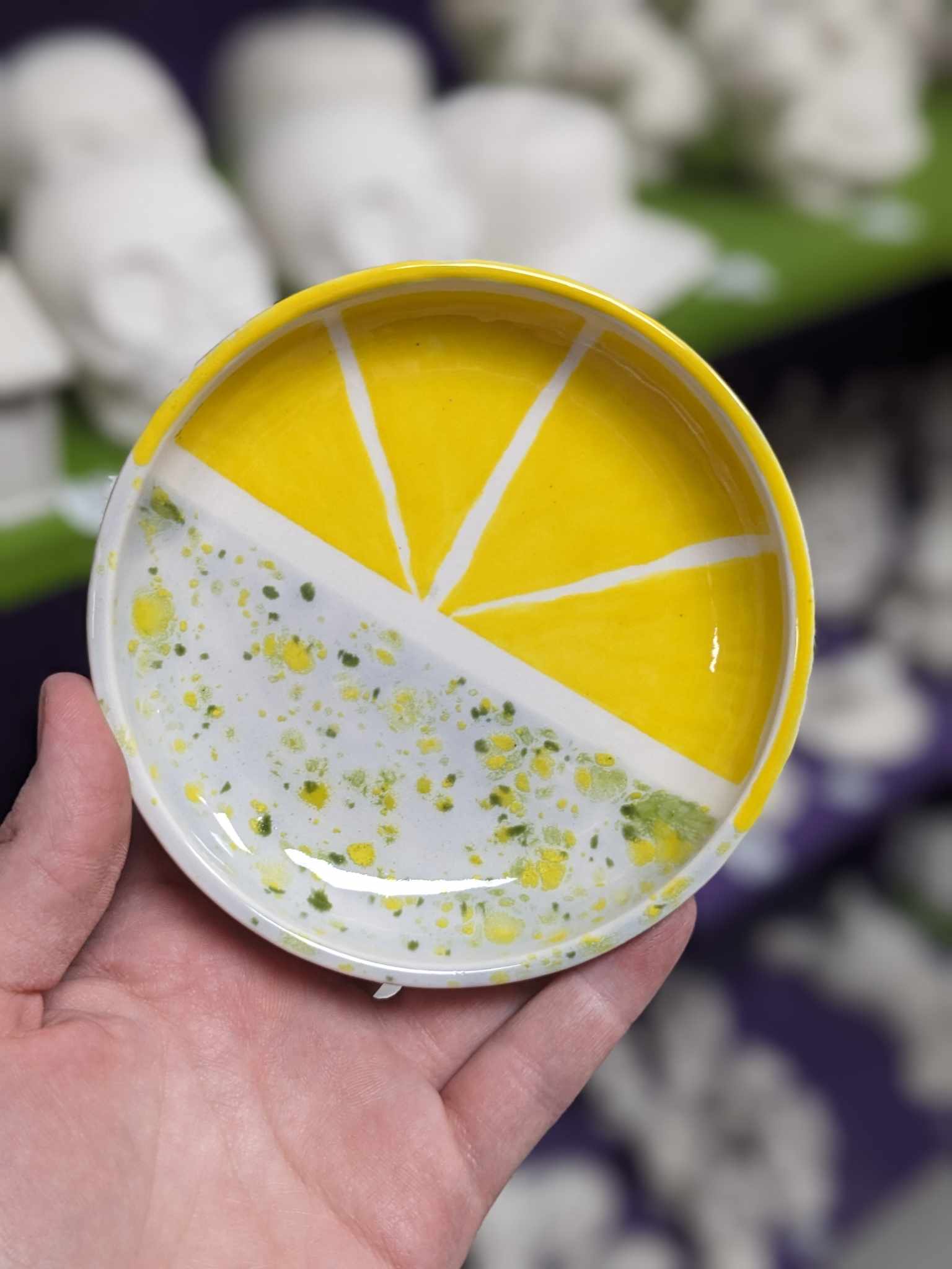 A person holding a bowl with yellow and white paint on it.