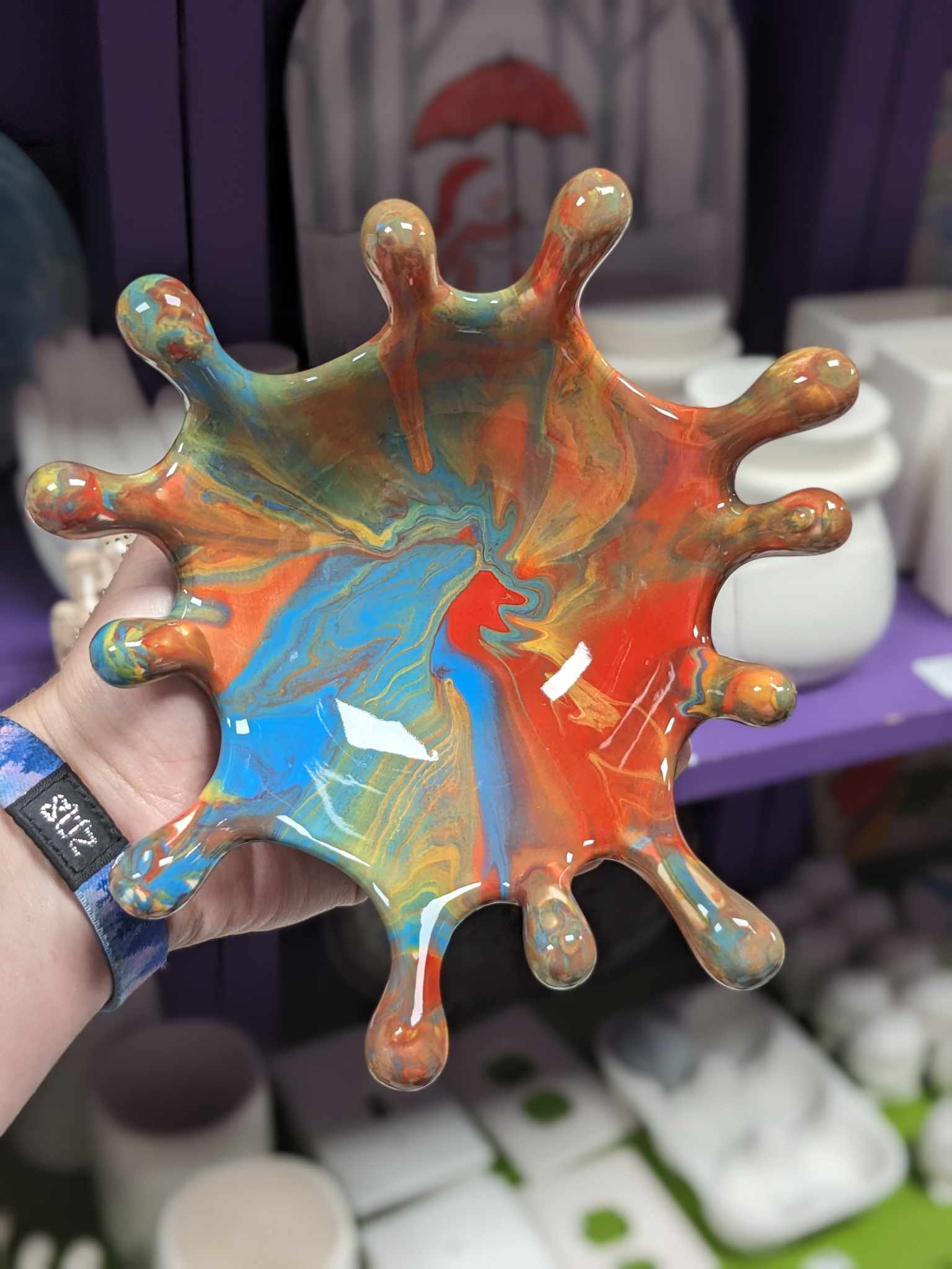 A person holding up a bowl with paint on it.