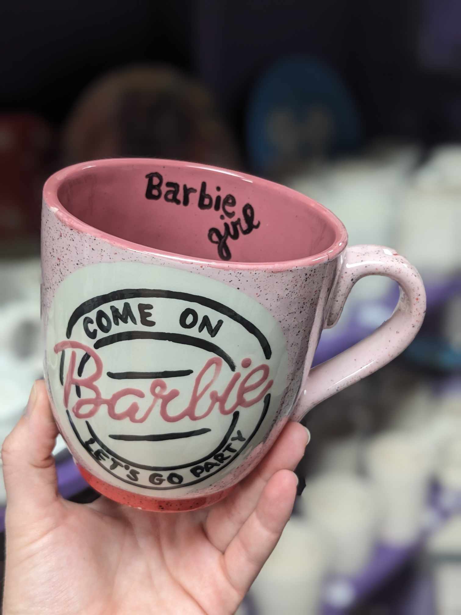 A pink coffee mug with the words " barbie " written on it.