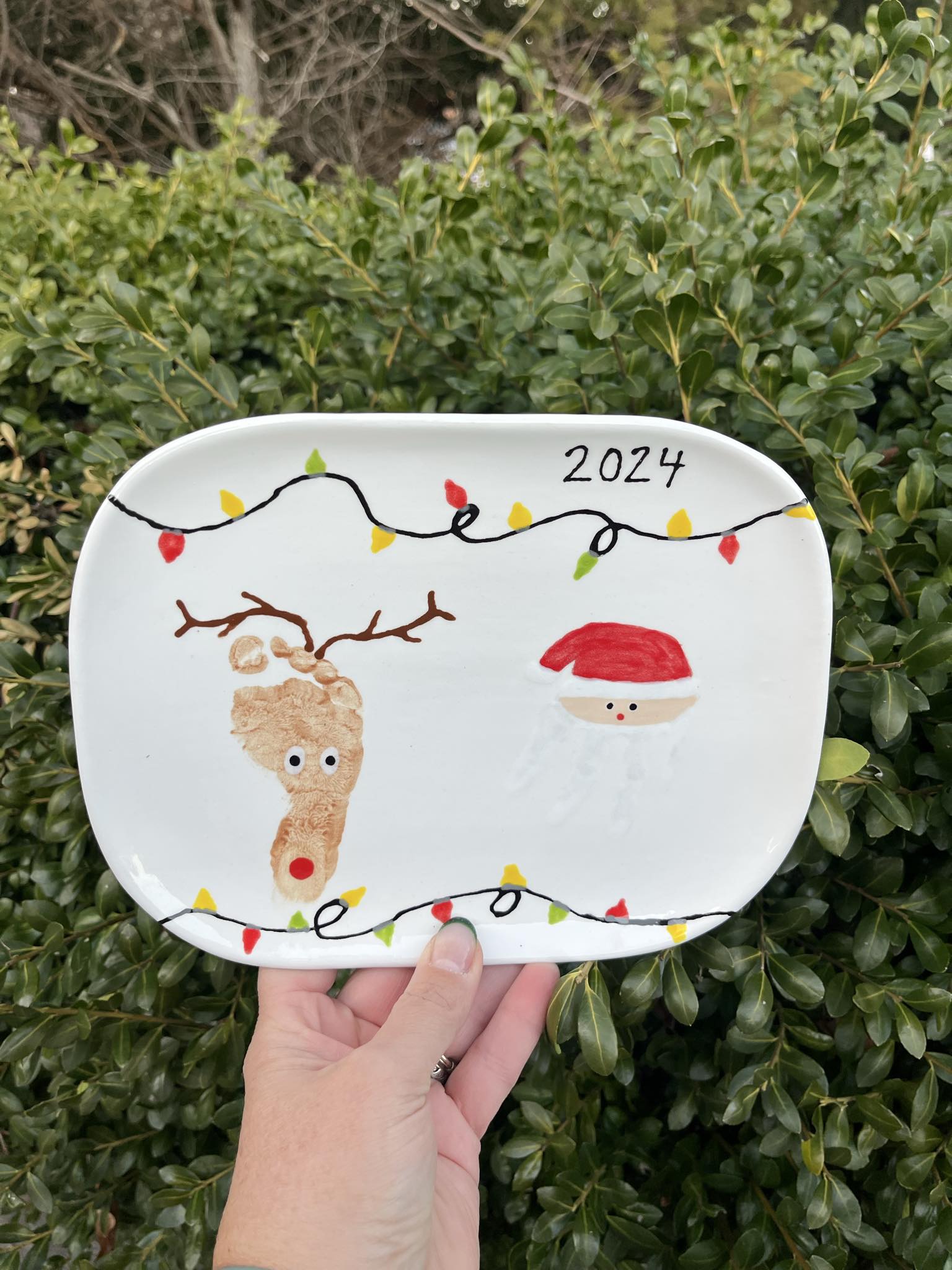 A person holding onto a plate with a picture of a reindeer and santa clause.